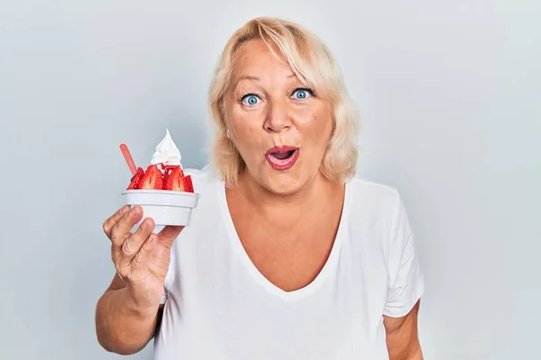 Middle Age Blonde Woman Eating Strawberry Ice Cream Scared Amazed — Stock Photo, Image