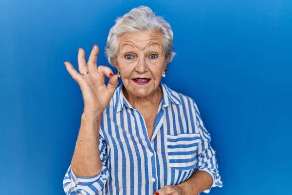 Mavi Arka Planda Gri Saçlı Yaşlı Kadın Gülümsüyor Parmaklarıyla Tamam — Stok fotoğraf