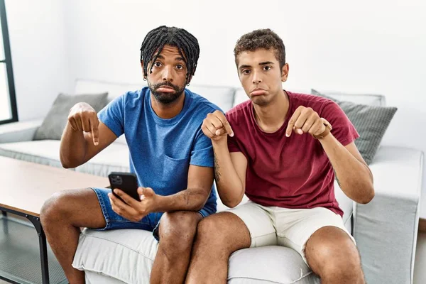 Mladí Hispánští Muži Kteří Používají Smartphone Sedí Doma Pohovce Ukazují — Stock fotografie