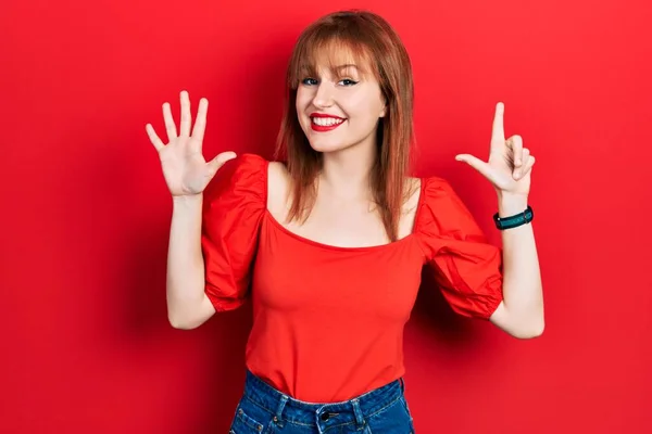 Rudowłosa Młoda Kobieta Ubrana Luźną Czerwoną Koszulkę Pokazuje Wskazuje Palcami — Zdjęcie stockowe