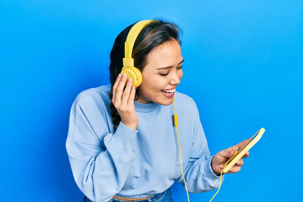 Young Hispanic Girl Using Smartphone Headphones Smiling Laughing Hard Out — Stockfoto