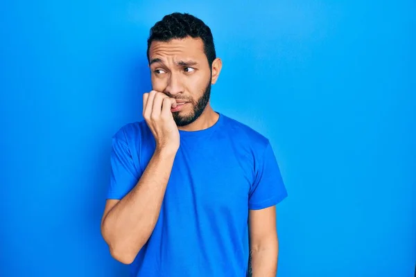 髭を生やしたヒスパニック系の男性は 口の爪をかむ上で手でストレスと緊張を見てカジュアルな青のTシャツを着ていた 不安の問題 — ストック写真