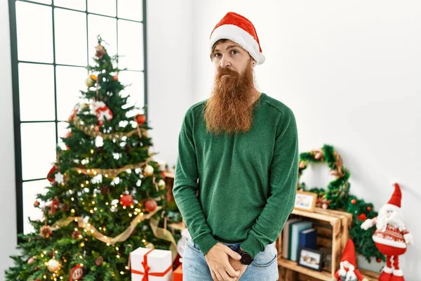 Κοκκινομάλλης Μακριά Γενειάδα Φοράει Χριστουγεννιάτικο Καπέλο Δίπλα Στο Χριστουγεννιάτικο Δέντρο — Φωτογραφία Αρχείου