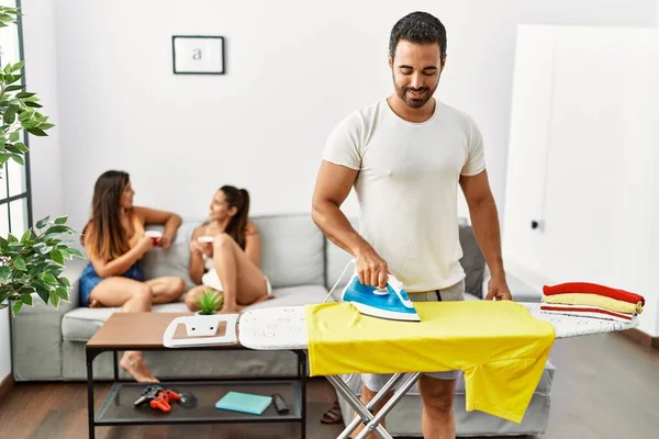 Mann Lächelt Glücklich Beim Bügeln Von Tüchern Wohnzimmer Während Frauen — Stockfoto