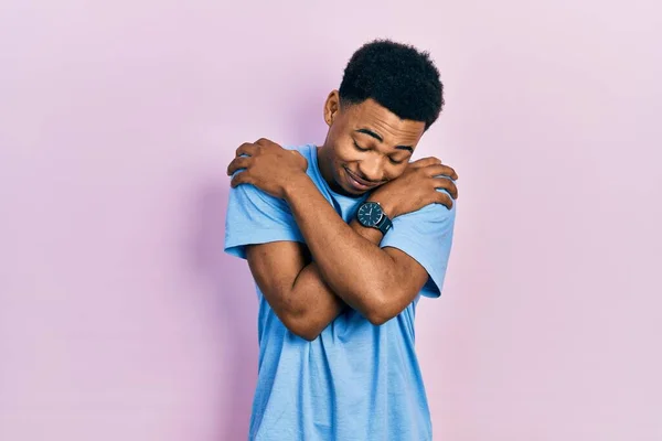 Young African American Man Wearing Casual Blue Shirt Hugging Oneself — стокове фото