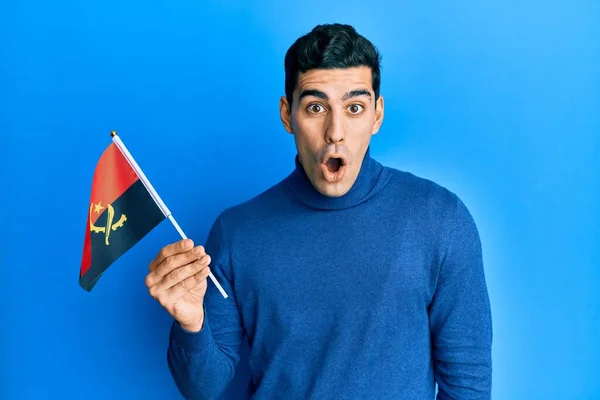 Snygg Hispanic Man Som Håller Angola Flagga Rädd Och Förvånad — Stockfoto