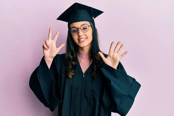 年轻的惊慌失措的女人 戴着毕业典礼帽 身穿礼袍 用手指指着八号 面带微笑 自信而快乐 — 图库照片