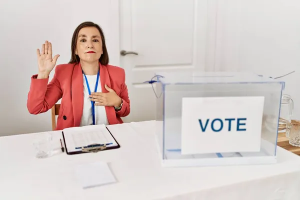 Piękna Latynoska Kobieta Średnim Wieku Siedząca Wyborach Politycznych Przysięgająca Ręką — Zdjęcie stockowe