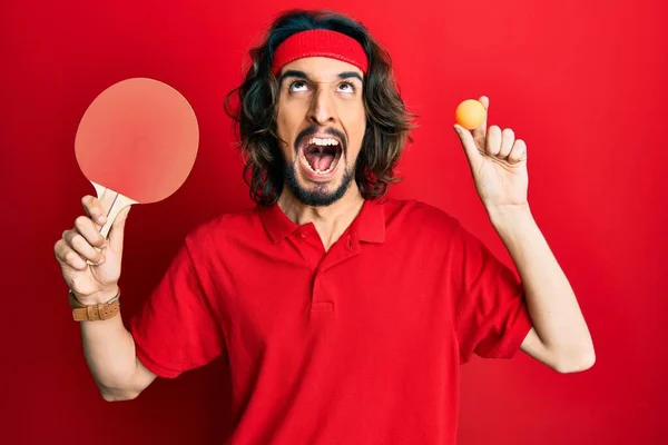 Joven Hispano Sosteniendo Raqueta Roja Ping Pong Bola Enojada Loca —  Fotos de Stock