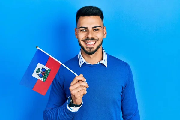 Joven Hombre Hispano Con Barba Sosteniendo Bandera Haití Luciendo Positivo —  Fotos de Stock