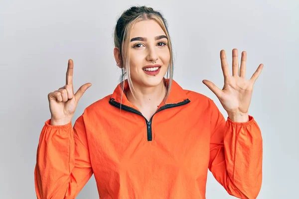 스포츠 운동복을 자신감 행복하게 웃으면서 손가락으로 번째를 가리키는 현대의 아가씨 — 스톡 사진
