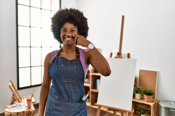 若いアフリカ系アメリカ人の女性は アートスタジオで顔と鼻に手指で指してアフロヘアで 陽気に笑っています 美の概念 — ストック写真
