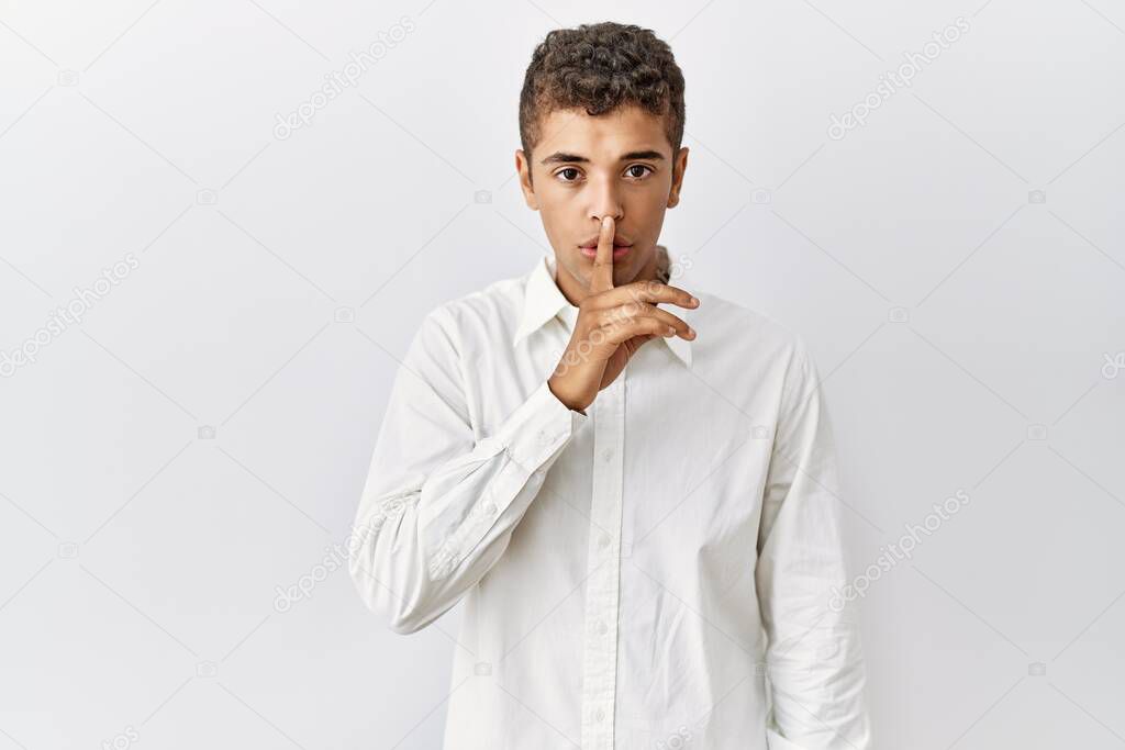 Young handsome hispanic man standing over isolated background asking to be quiet with finger on lips. silence and secret concept. 