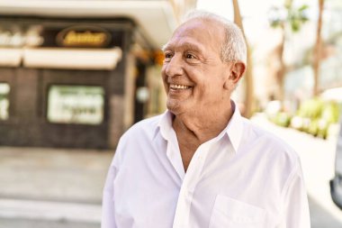 Güneşli bir günde kır saçlı son sınıf öğrencisi dışarıda mutlu mesut dikiliyor. Emeklilik için 70 'lerinde mutlu bir gülümseme.