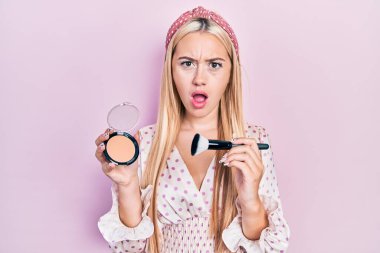 Elinde bronzlaştırıcı ve fırça tutan genç sarışın kız şaşkınlık ve şaşkınlık dolu bir ifade, korku ve heyecanlı bir yüz ifadesiyle dehşete düştü.. 