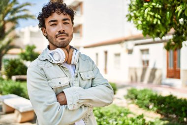 Yakışıklı, sakallı, neşeli, güneşli bir günde kulaklık takan bir İspanyol.