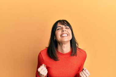 Genç İspanyol kadın gündelik kıyafetler giyiyor çok mutlu ve heyecanlı kazanan jestler yapıyor kolları havada, gülümsüyor ve başarı için bağırıyor. kutlama konsepti. 
