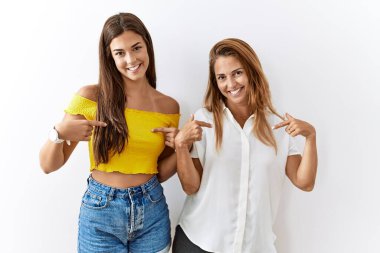 Mother and daughter together standing together over isolated background looking confident with smile on face, pointing oneself with fingers proud and happy. 