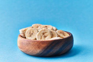  Mavi arka planda bir kase muz dilimi.