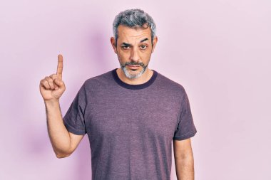 Yakışıklı, orta yaşlı, gri saçlı, işaret parmağı kuşkucu ve gergin, sorun yüzünden kaşlarını çatan bir adam. negatif kişi. 