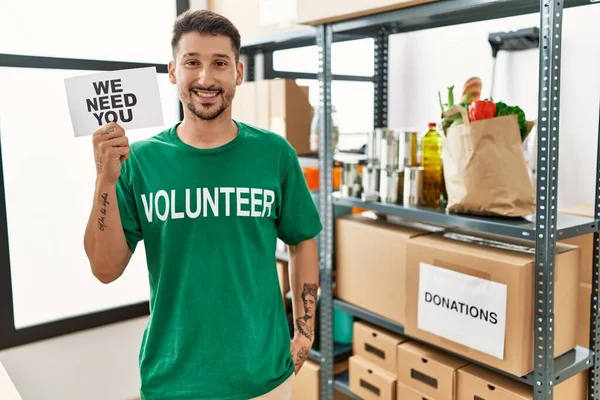 Young Hispanic Man Wearing Volunteer Shirt Holding Need You Banner — Foto de Stock