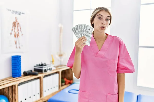 Young Physiotherapist Woman Working Pain Recovery Clinic Holding Dollars Scared — Foto de Stock