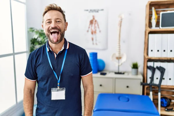 Middle Age Physiotherapist Man Working Pain Recovery Clinic Sticking Tongue — Stockfoto