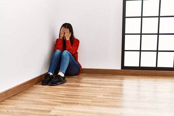 Young latin woman sitting on the floor crying at empty room