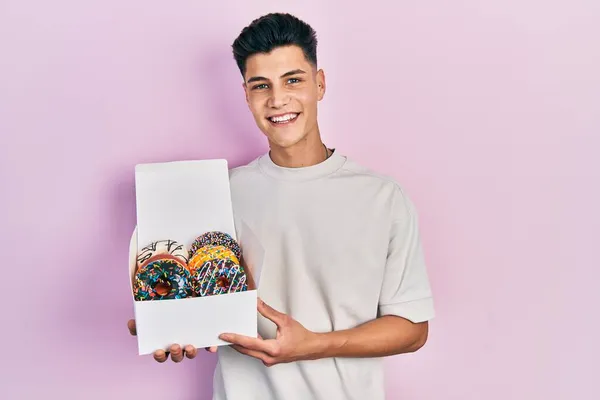 Joven Hombre Hispano Sosteniendo Caja Sabrosas Rosquillas Coloridas Que Parecen —  Fotos de Stock