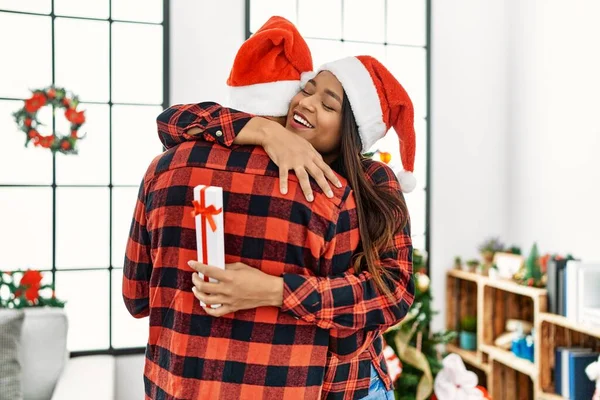 Młoda Latynoska Para Uśmiechnięta Szczęśliwa Przytulona Trzymająca Świąteczny Prezent Domu — Zdjęcie stockowe