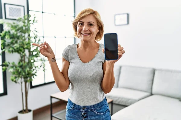 Mulher Loira Meia Idade Trabalhando Segurando Smartphone Mostrando Tela Sorrindo — Fotografia de Stock