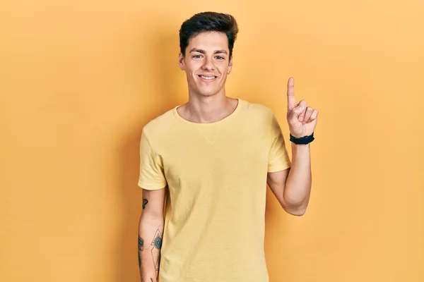 Gündelik Sarı Tişört Giyen Spanyol Genç Adam Bir Numarayı Gösterip — Stok fotoğraf