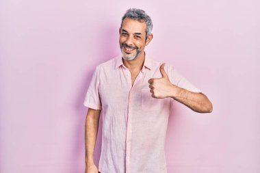 Handsome middle age man with grey hair wearing casual shirt doing happy thumbs up gesture with hand. approving expression looking at the camera showing success. 
