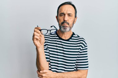 Orta yaşlı İspanyol bir adam, günlük kıyafetler giyiyor ve elinde gözlük tutuyor. Komik yüzüyle yanaklarını şişiriyor. Ağzı havayla şişer, havayı yakalar.. 