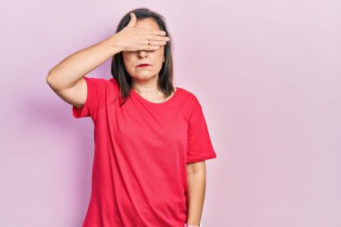 Orta yaşlı İspanyol kadın gündelik giysiler giyip gözlerini eliyle kapatıyor, ciddi ve üzgün görünüyor. Görme, saklama ve reddetme konsepti 