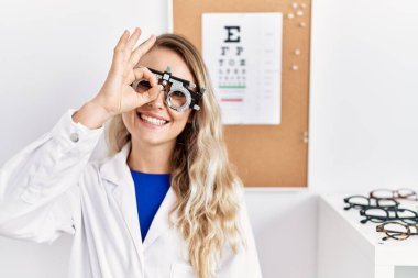 Klinikte optometri gözlüğü takan genç ve güzel bir gözlükçü kadın gülümsüyor. 