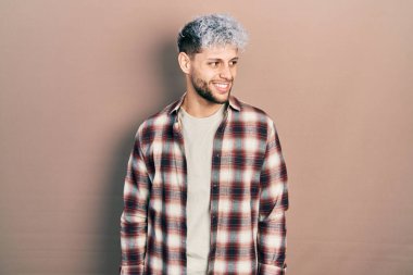 Modern boyalı saçlı, sıradan gömlekli, yüzünde gülümseme ve doğal ifadeyle yan yana bakan İspanyol bir genç. Kendinden emin gülen. 