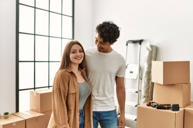 Genç çift mutlu bir şekilde gülümsüyor ve yeni evlerinde birbirlerine sarılıyorlar..