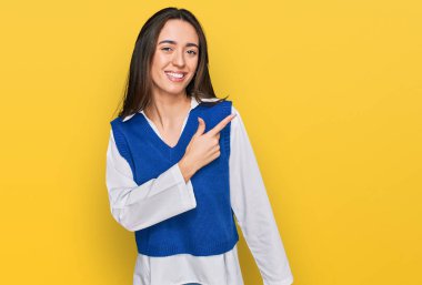 Yüzünde mutlu ve doğal bir ifade olan, elleri ve parmaklarıyla işaret eden, güler yüzlü, gündelik kıyafetler giyen genç İspanyol kız. 