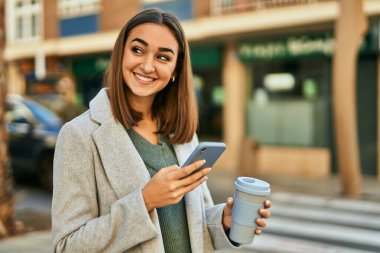 Genç İspanyol kız akıllı telefon kullanıyor. Şehirde kahve içiyor..