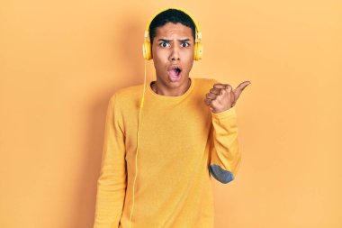 Kulaklıkla müzik dinleyen Afro-Amerikalı genç bir adam el ile işaret ederek şaşırdı, ağzı açık hayret içinde kaldı.. 