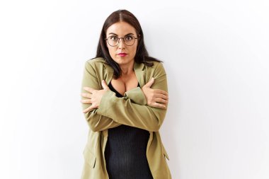 Genç esmer kadın izole edilmiş arka planda duruyor. Kış soğuğu yüzünden titriyor ve donuyor. Yüzünde üzgün ve şok ifadesi var. 