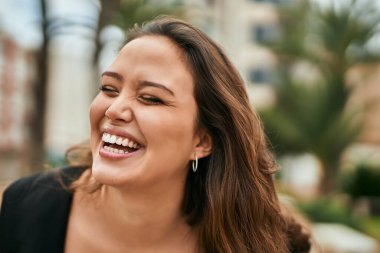 Genç İspanyol kadın gülümseyerek şehirde mutlu mesut dikiliyor..