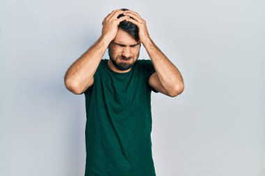 Genç İspanyol adam, günlük beyaz tişört giyiyor. Baş ağrısı çekiyor. Acı ve migren yüzünden çaresiz ve stresli. Eller başının üstünde.. 