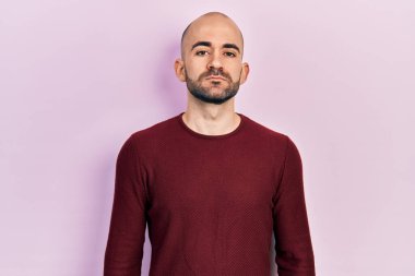 Sıradan kıyafetler giyen genç kel bir adam. Yüzünde ciddi bir ifadeyle rahatlamış. Basit ve doğal bir şekilde kameraya bakıyorsun.. 