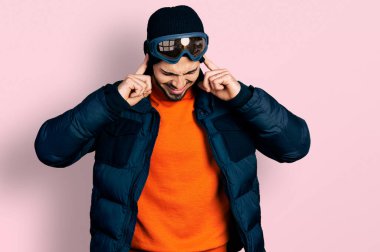 Kar maskesi takan, kar maskesi takan, kulaklarını parmaklarıyla kapatan, yüksek sesli müzik sesi için rahatsız edici ifadeleri olan İspanyol genç bir adam. sağır kavramı. 