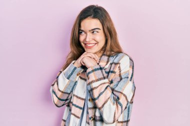 Kafkasyalı genç bir kız günlük kıyafetler giyiyor. Gergin ve heyecanlı bir şekilde gülüyor. Elleri çenesinde yan tarafa bakıyor. 