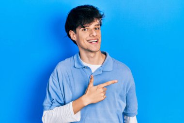 Yakışıklı hippi, klasik giyinmiş genç adam gülümsüyor, gülümsüyor, eli ve parmağı yana bakıyor. 