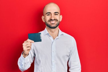 Genç kel adam hafızasını koruyor. Olumlu ve mutlu görünüyor. Dişlerini gösteren bir gülümsemeyle ayakta duruyor ve gülümsüyor. 