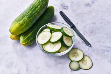  Mermer bir yüzeyde bir kase salatalık dilimi